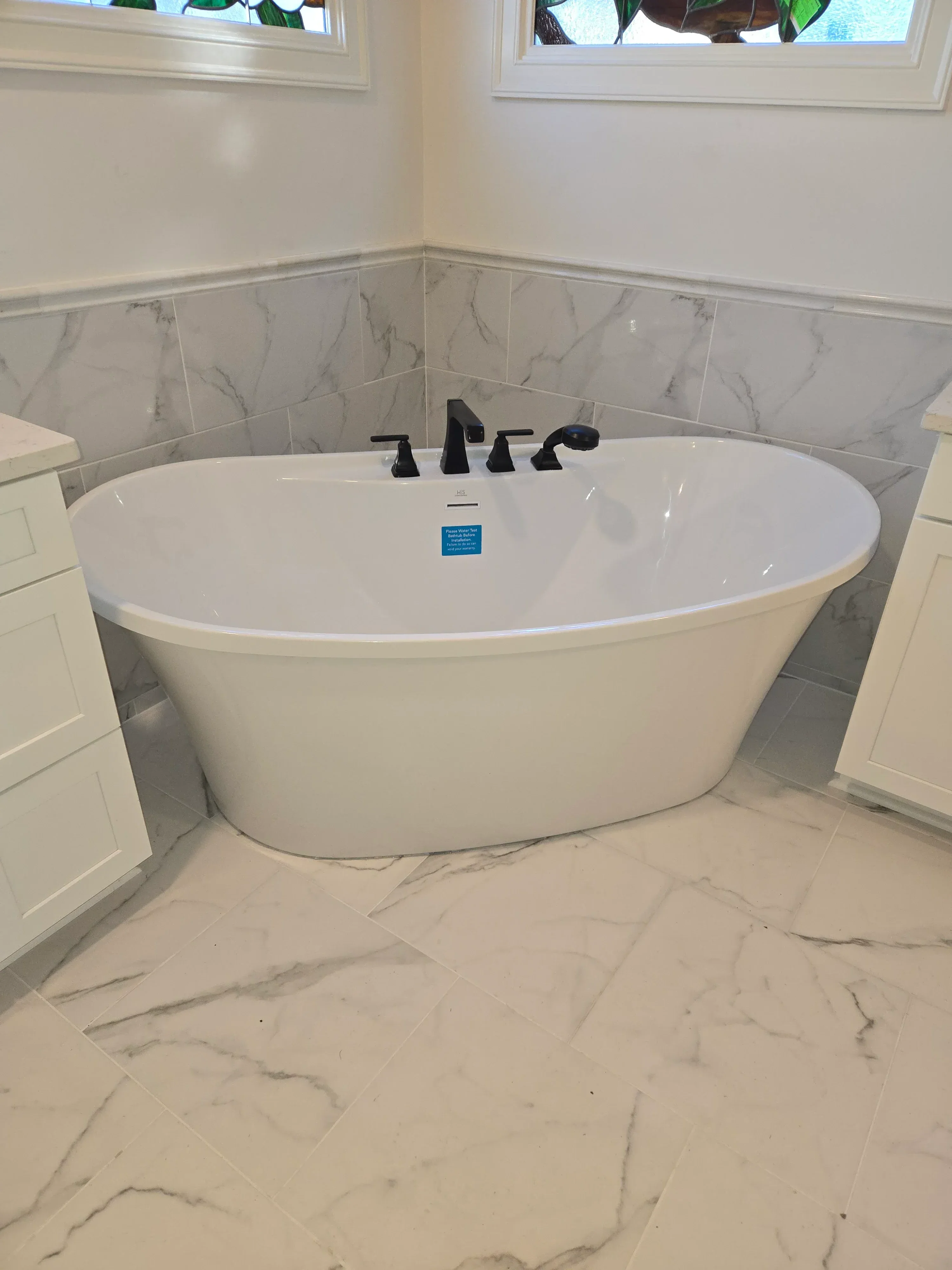 White oval vessel sink with chrome faucet on marble tile bathroom wall