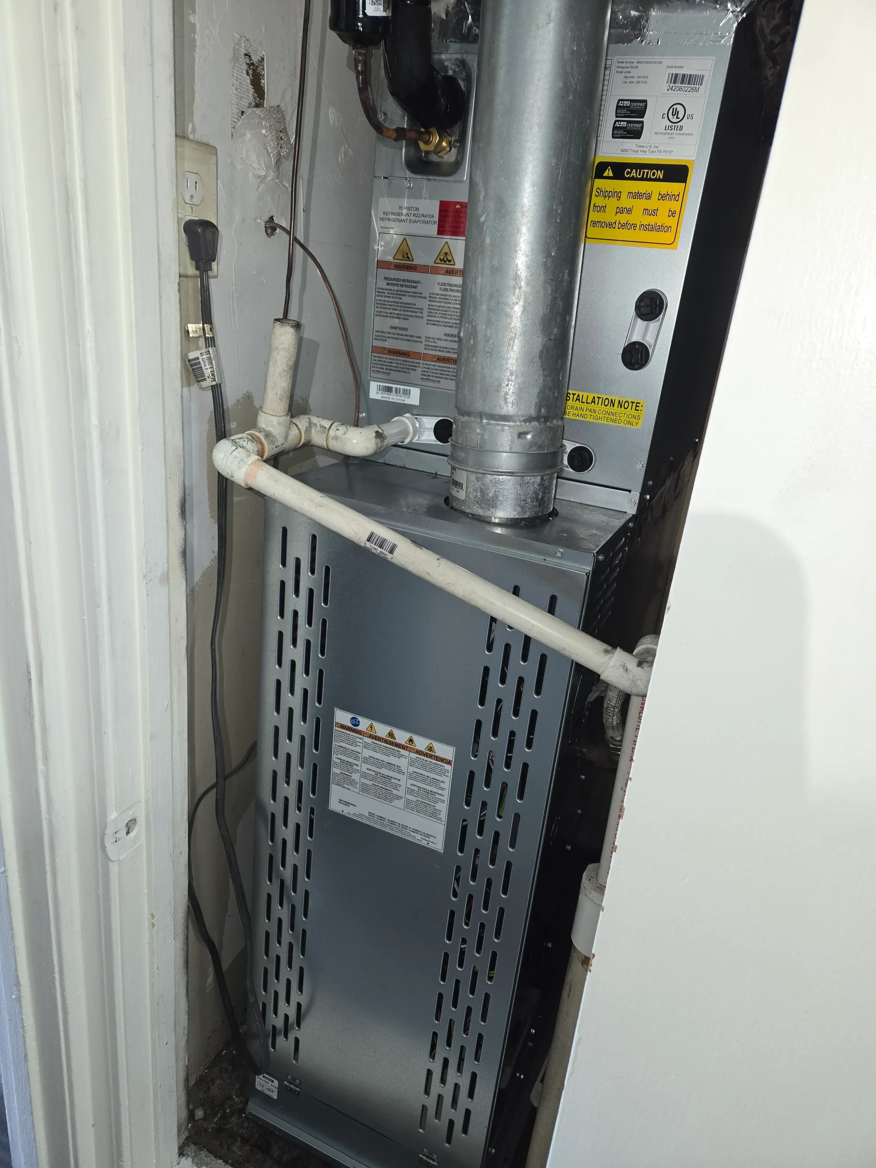 Tankless water heater with PVC venting, gas connections, and mounting hardware installed