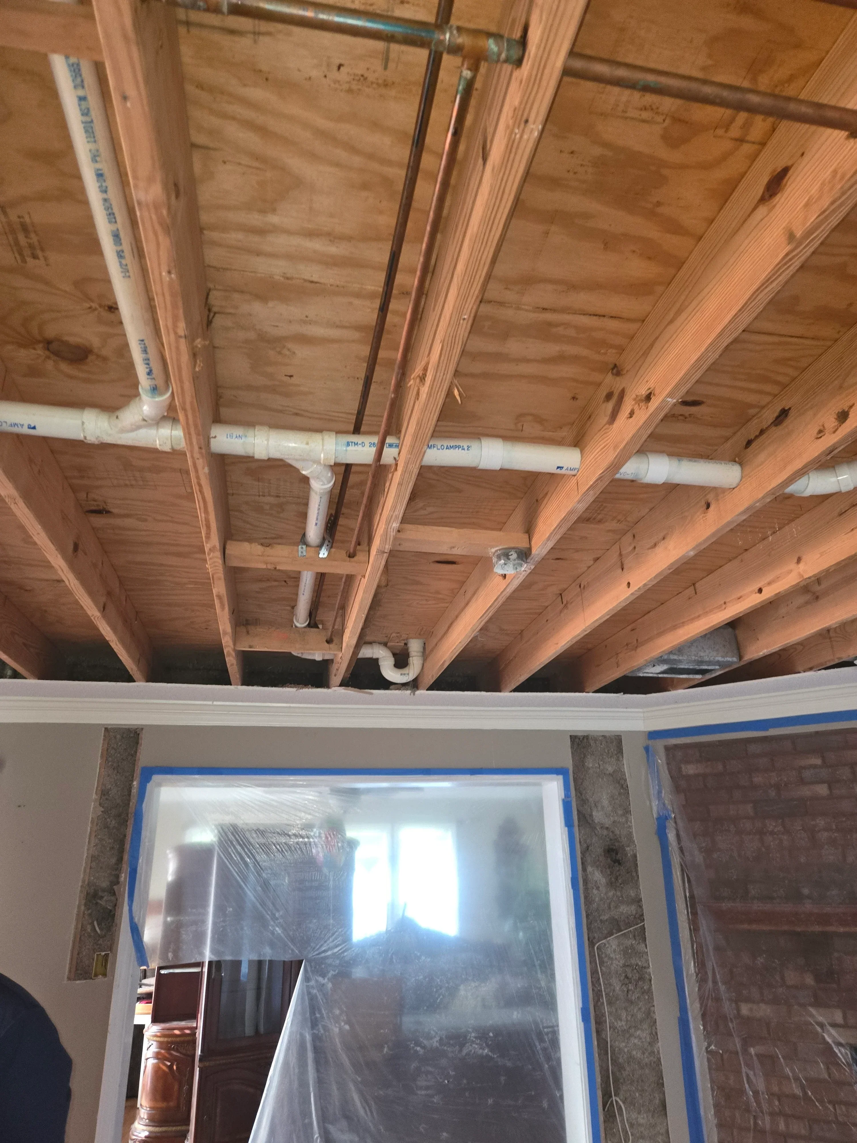 Copper and PVC HVAC ductwork installed in wood-framed wall cavity with labeled insulation