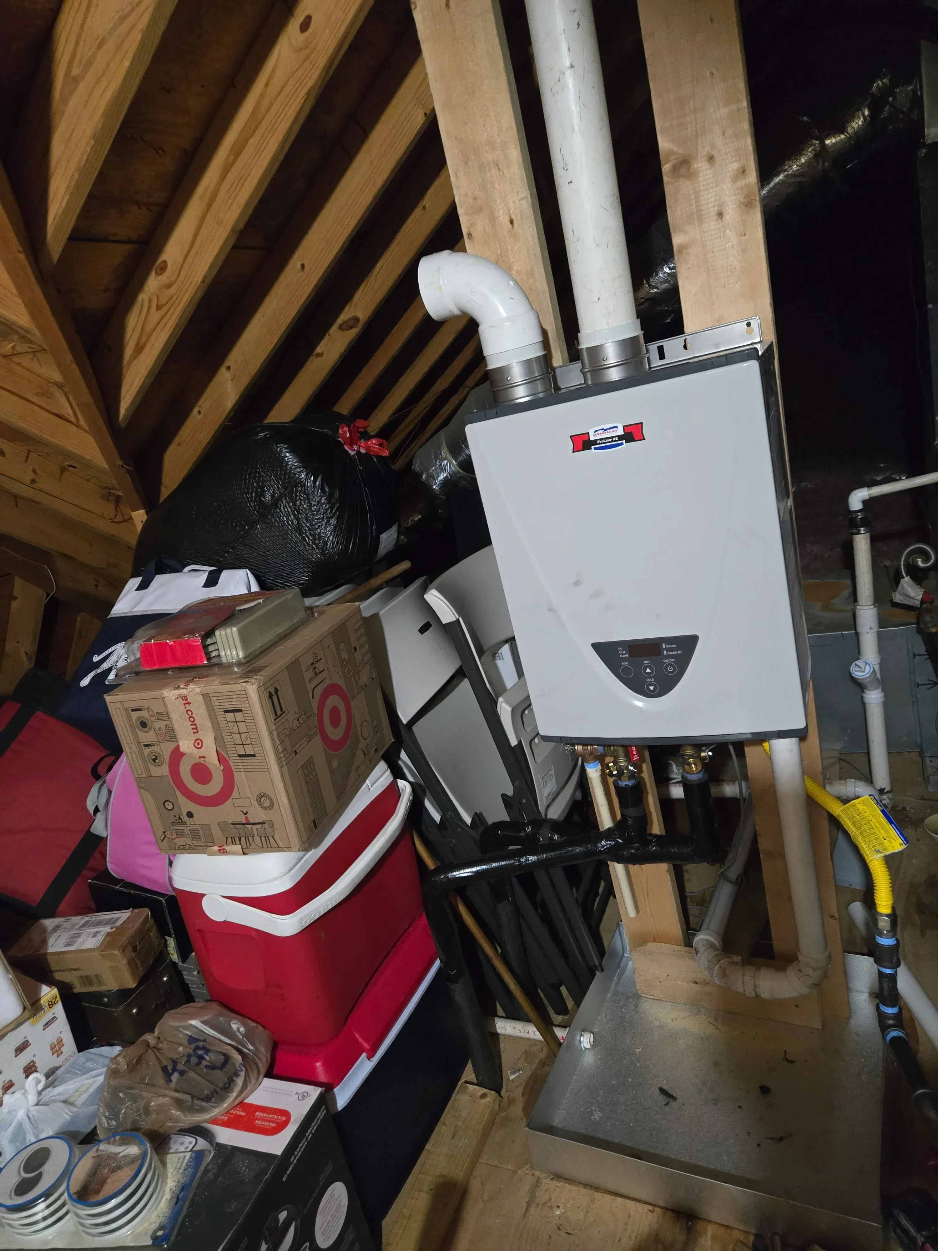 Tankless water heater with white casing, PVC venting, and copper piping installed in utility space