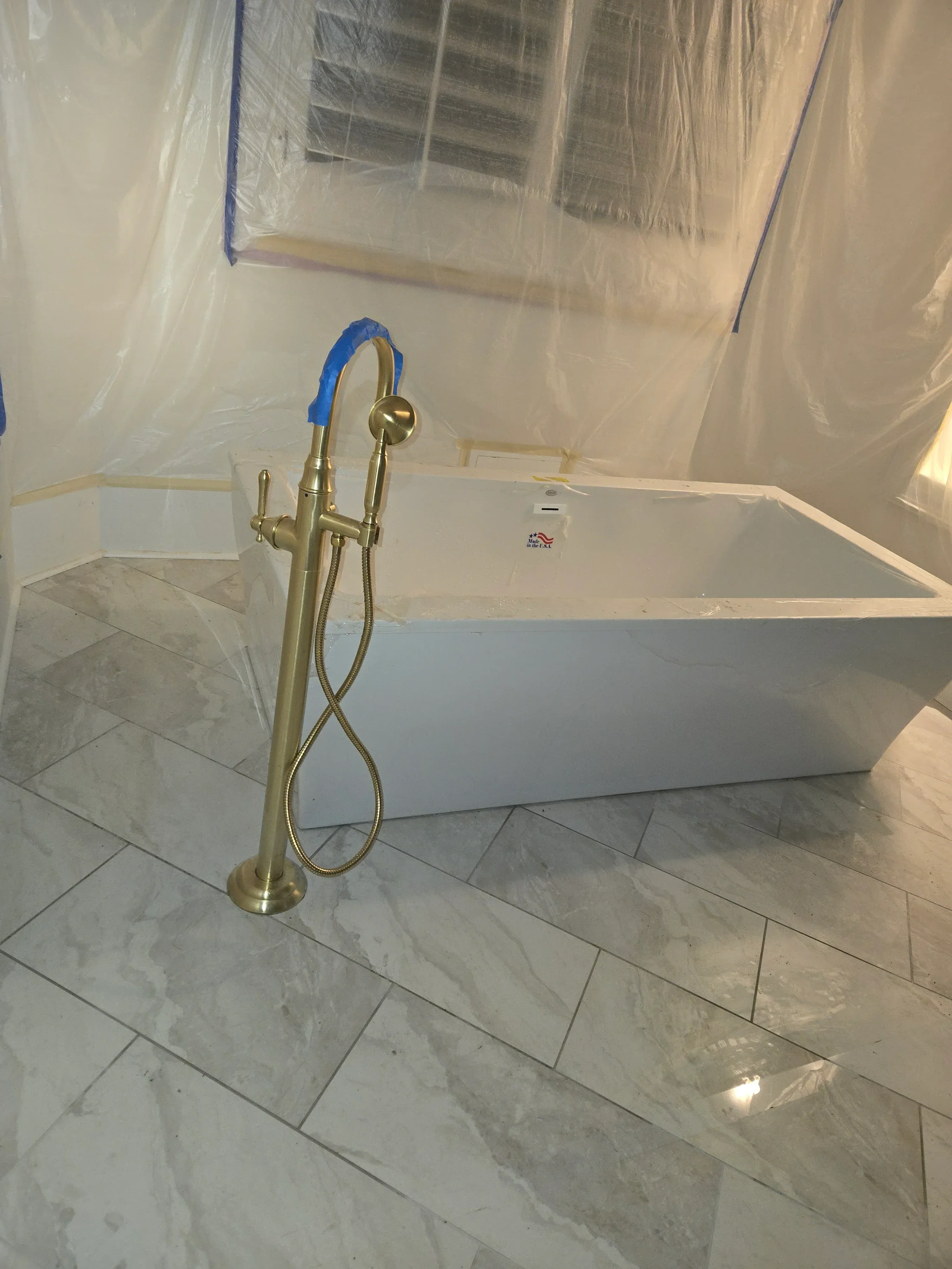 Brass shower valve and arm installed on marble tile bathroom walls during construction