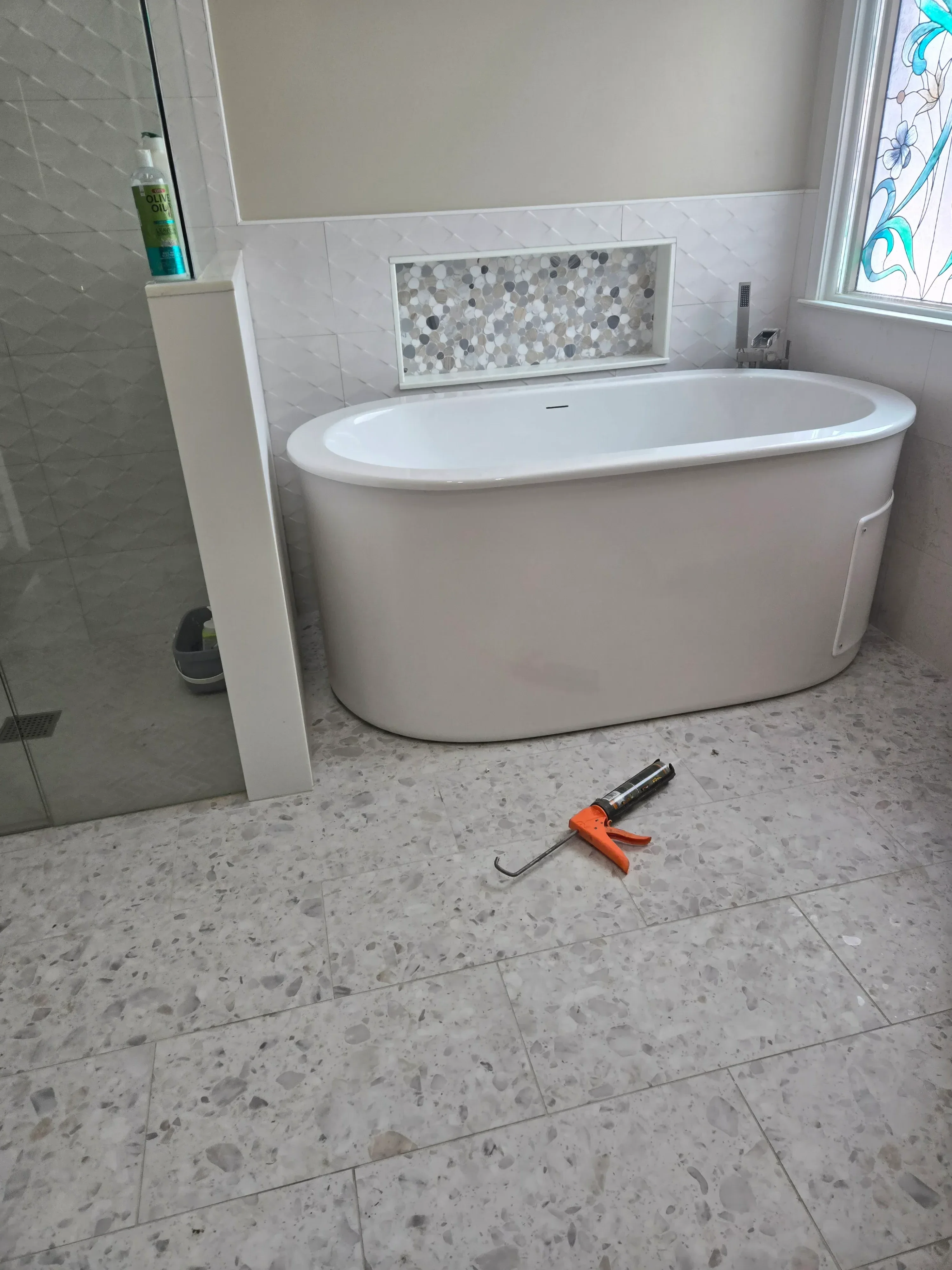 Round exhaust fan with white trim ring installed in terrazzo tile bathroom ceiling