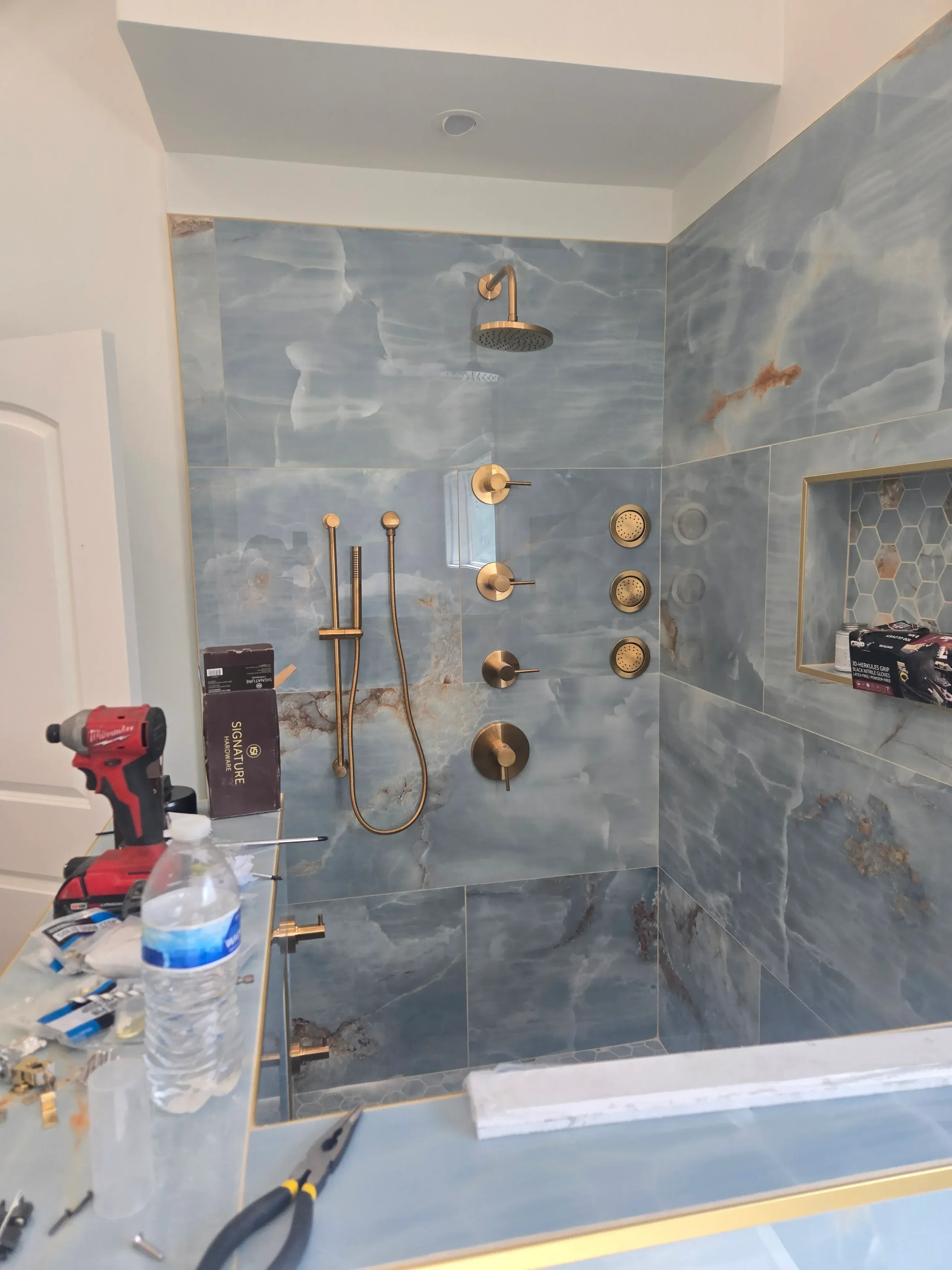 Gray marble tile bathroom with brass plumbing fixtures and hardware installation