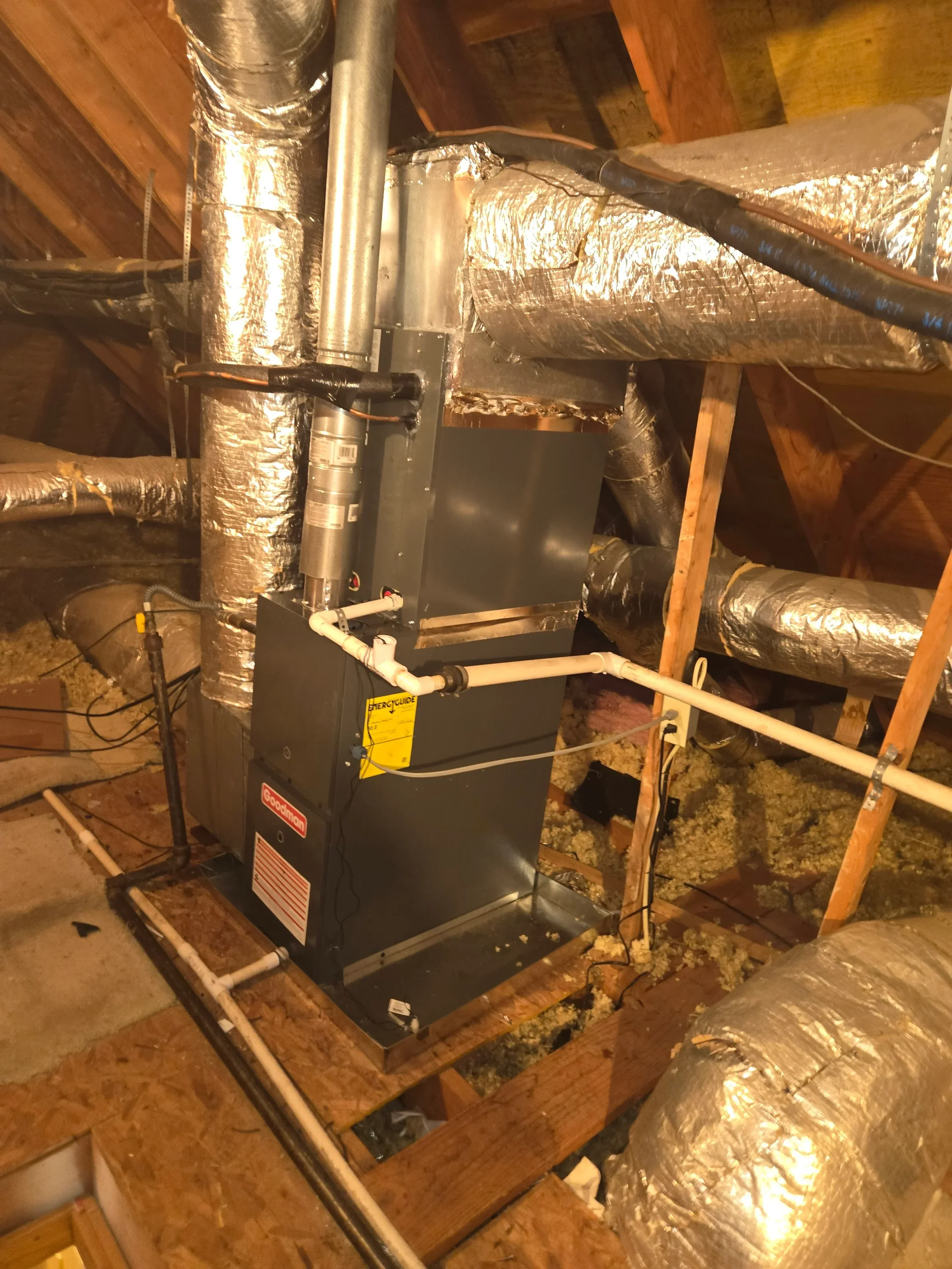 Installed HVAC furnace with insulated ductwork, metal piping, and flexible connectors in attic space